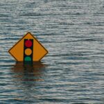 Traffic sign submerged in murky water, signs of flooding.