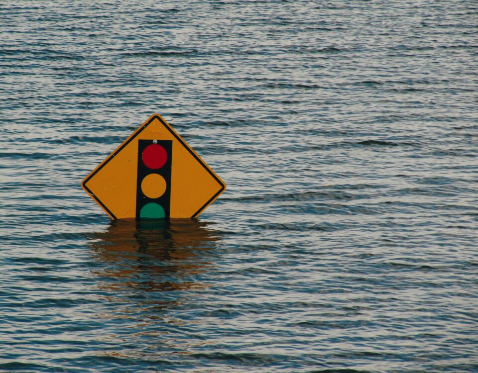 Traffic sign submerged in murky water, signs of flooding.